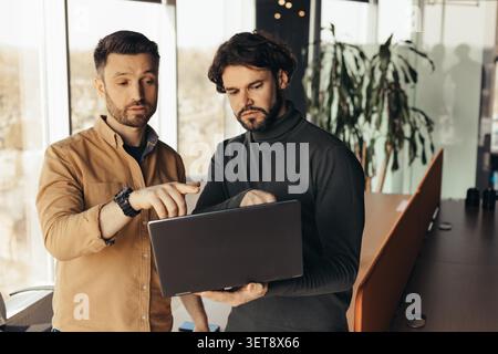 Two Men Analyzing Data On Laptop In Office, Business Concept Stock Photo