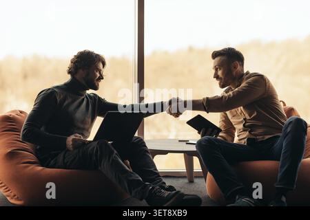 Two Men Shaking Hands While Working Together In Modern Office, Business Concept Stock Photo