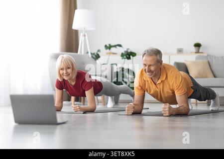 Elderly Caucasian Couple Doing Plank Exercise At Home Using Laptop, Fitness Concept Stock Photo
