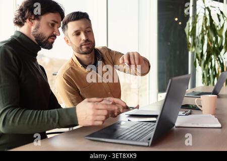 Two Men Collaborating On Laptop In Modern Office, Business Concept Stock Photo