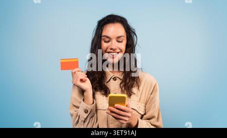 Smiling Young Woman Holding Credit Card And Smartphone, Shopping Concept Stock Photo