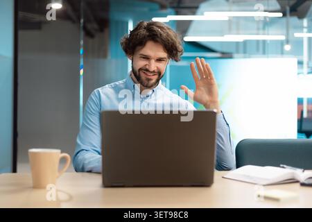 Happy Young Caucasian Man Working From Home, Video Call With Laptop In Modern Office Setting Stock Photo
