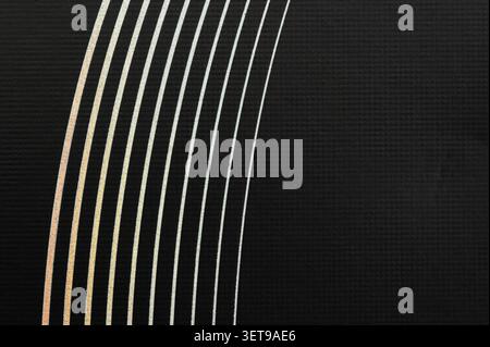 Curved lines in silver and gold stretch across a black surface creating a simple design that draws attention without any center point. Stock Photo