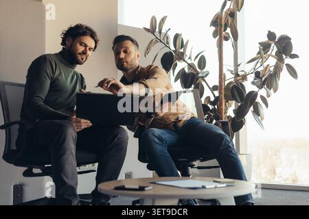 Two Male Professionals Collaborating On Project In Modern Office Setting, Business Concept Stock Photo