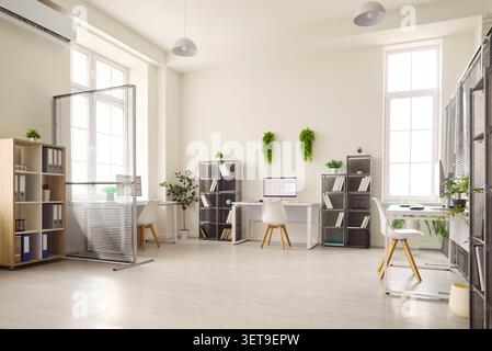 Bright modern office workspace with computers, partitions and indoor plants Stock Photo