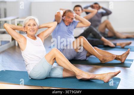 Seniors in sportswear doing exercises at pilates workout Stock Photo