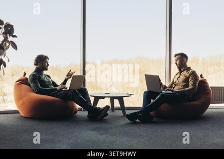 Two Young Men Working Together On Laptops In Modern Office, Business Concept Stock Photo