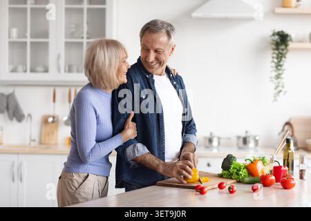 Happy Elderly Caucasian Couple Preparing Healthy Meal Together In Modern Kitchen, Cooking Concept Stock Photo
