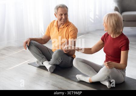 Happy Elderly Caucasian Couple Practicing Yoga Together At Home, Weight Loss Concept Stock Photo