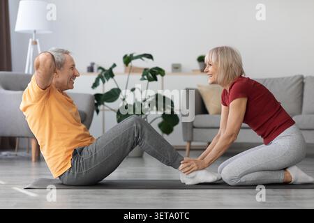 Happy Elderly Couple Practicing Yoga At Home, Engaging In Stretching Exercises, Fitness Concept Stock Photo