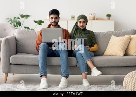 Young Man And Woman Working On Laptops Together At Home, Focused And Productive, Working Lifestyle Concept Stock Photo
