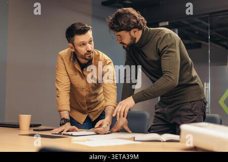 Two Young Men Collaborating And Discussing Ideas In Modern Office, Business Concept Stock Photo