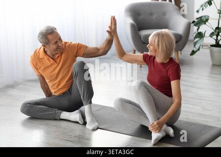 Happy Senior Caucasian Couple Exercising Together At Home, Engaging In Stretching Routine Stock Photo