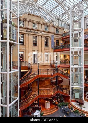 A restored 19th-century merchant building featuring a multi-level atrium, grand staircase, and modern glass elevators at Princes Square. Stock Photo