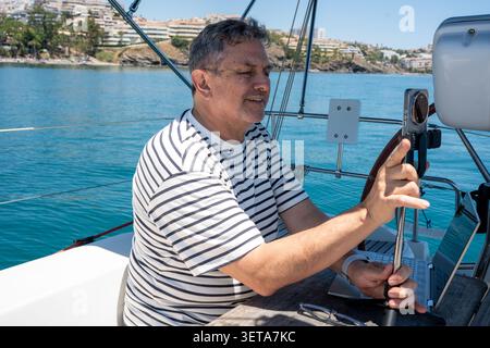 Man sailing enjoying remote work and leisure on boat Stock Photo