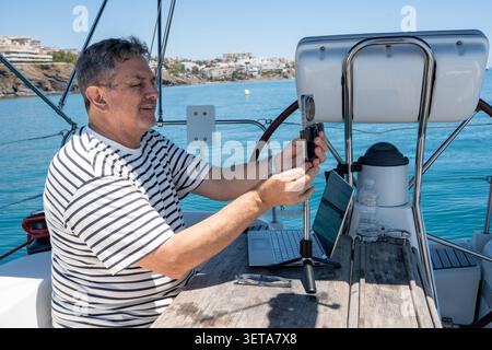 Man working remotely on sailboat setting up smartphone Stock Photo