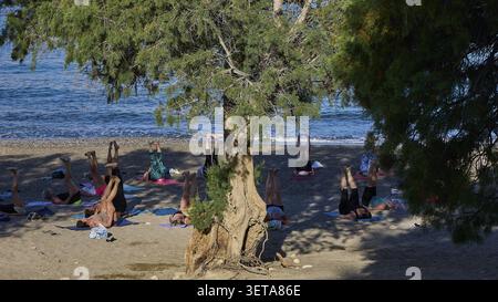 Group of people doing yoga on the beach under a shady tree, Matala, South Coast, Crete, Greek Islands, Greece Stock Photo