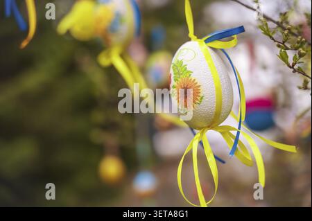 White easter eggs with blue and yellow ribbons on a tree Stock Photo