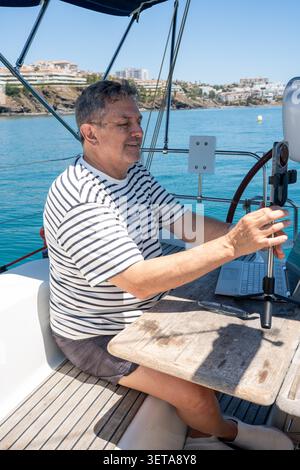 Man working remotely on boat embracing digital nomad lifestyle Stock Photo