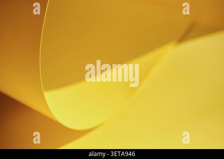 Yellow paper forms abstract curves and dynamic waves with shadows Stock Photo