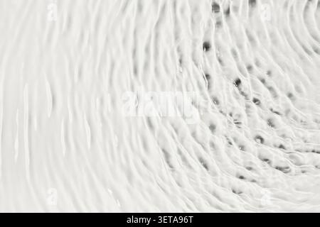 A clear water surface that forms abstract waves and ripples, as a calm background Stock Photo