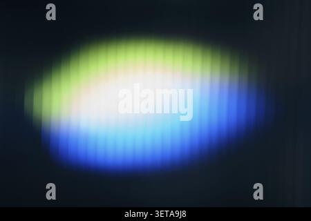 Abstract glowing light that creates a glowing green, white and blue gradient pattern on a dark background Stock Photo