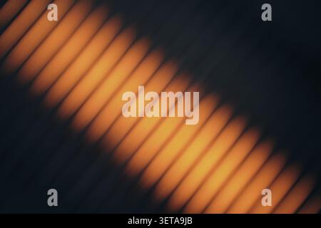 Orange light that creates a blurry diagonal line pattern on a dark background Stock Photo