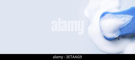 Blue sponge surrounded by white soap foam, banner format Stock Photo