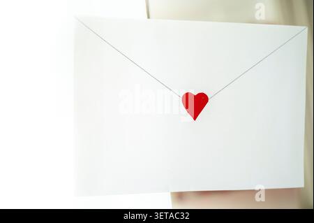 Craft envelope made of white paper with a small cute heart. the envelope is located on the background of the interior. horizontal photo Stock Photo