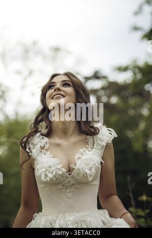 Stunning Bride Gracefully Poses in Spring Park Among Blossoming Trees. Exuding Elegance, Romance and Timeless Charm. Soft Pink Wedding Dress with Euro Stock Photo