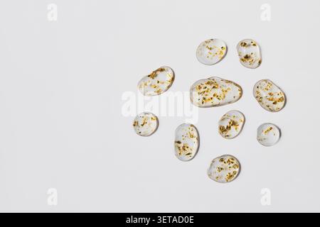 Transparent gel drops with gold flakes forming an abstract luxury background Stock Photo