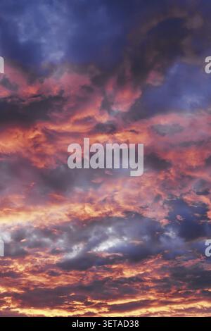 Sunset sky with colorful clouds illuminated with red and orange light Stock Photo