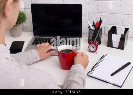 Woman drinking morning coffee in red cup and using touchpad Stock Photo