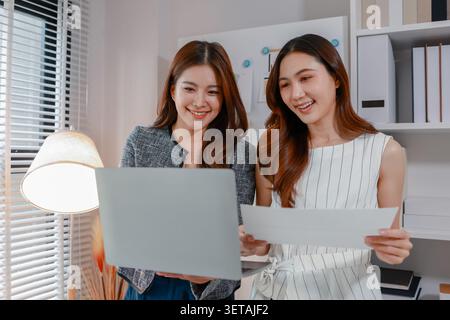 Two businesswomen collaborating on reports and performance charts, discussing business strategy, reviewing data analysis, presenting results, and plan Stock Photo