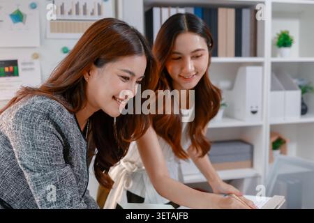 Two businesswomen collaborating on reports and performance charts, discussing business strategy, reviewing data analysis, presenting results, and plan Stock Photo