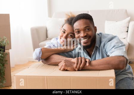 Afro Spouses Embracing Among Unpacked Moving Boxes In New Flat Stock Photo