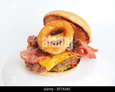 Big burger with beef patties, pickles, cheese, beef bacon, onion rings with special sauces isolated on a white background Stock Photo