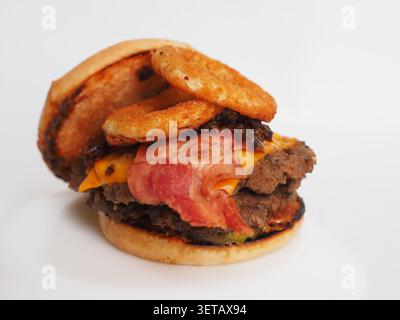 Big burger with beef patties, pickles, cheese, beef bacon, onion rings with special sauces isolated on a white background Stock Photo