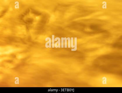 Golden amber glass texture macro with wavy translucent surface for warm abstract background Stock Photo