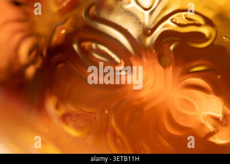 Amber embossed glass macro with ornate floral pattern and glossy glow for elegant abstract background Stock Photo