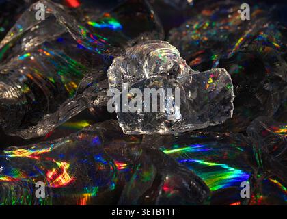 Clear crystal shard macro with rainbow prism refraction on dark surface for sparkling abstract background Stock Photo