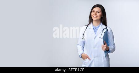 Smiling Female Doctor in a White Coat Poses Confidently in a Clinical Setting Stock Photo