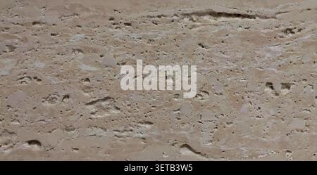 Close-up of a natural travertine stone surface showing characteristic pores, cavities, and horizontal layered striations in warm beige and cream tones. Stock Photo