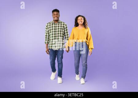 Couple Walks Hand in Hand on a Purple Background During a Photo Session in Daylight Stock Photo
