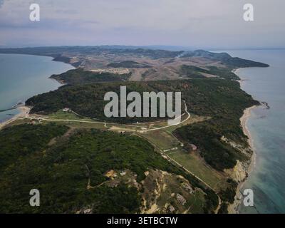An expansive aerial view captures a verdant peninsula stretching into the sea, flanked by sandy beaches and calm turquoise waters. The landscape featu Stock Photo