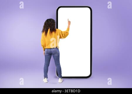 Person Interacts With a Large Mobile Device Screen in a Studio Setting With a Purple Background Stock Photo