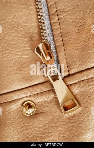 Golden zip slider and snap button on beige leather jacket closeup Stock Photo