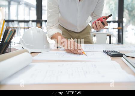 Engineer Reviewing Construction Plans with Tools in Office Envir Stock Photo