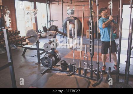 Fit man selecting bar from rack while working out at the gym Stock Photo