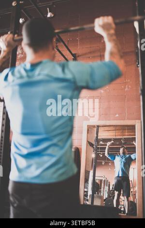Rear view of man lifting barbell above his head, view in mirror Stock Photo